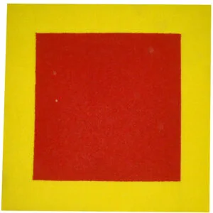 Imagem do Tapete Demarcador para Extintor vista de cima. O tapete é quadrado, com uma grande área vermelha no centro cercada por uma moldura amarela grossa. A textura mostra as tramas da fibra de vinil. O tapete está sobre um piso claro.